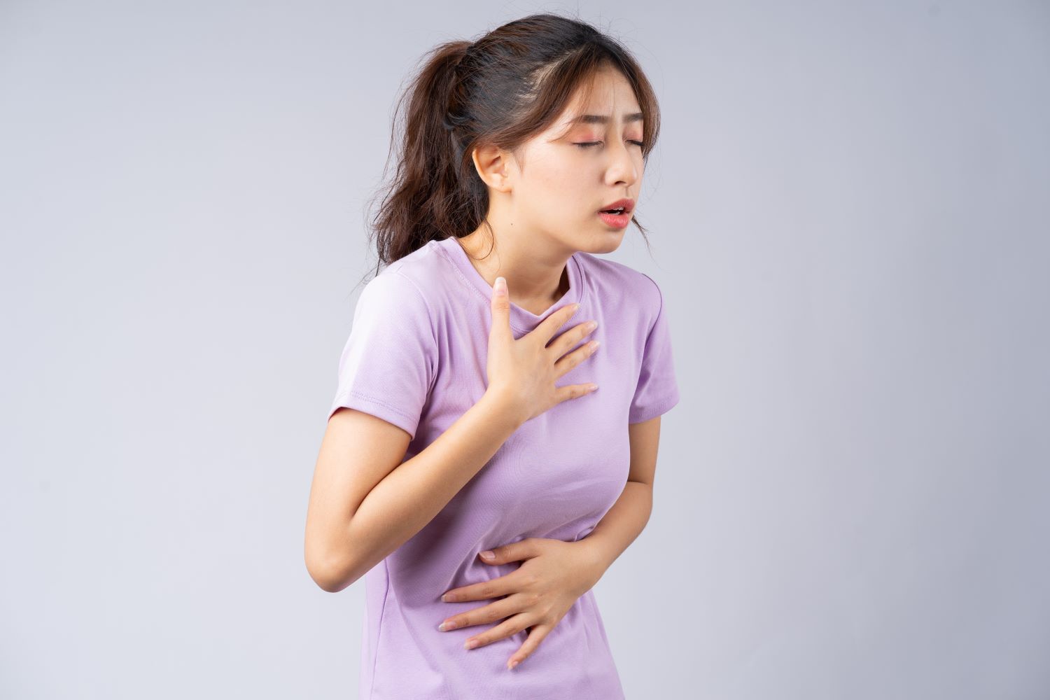 mulher com esofagite de refluxo com a mão na altura do esôfago